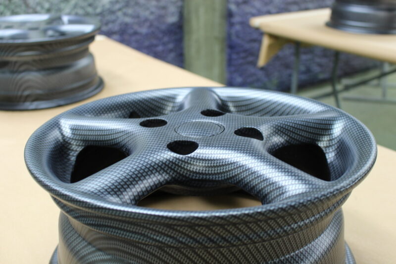 Car alloy wheels coated in carbon fibre painted magenta