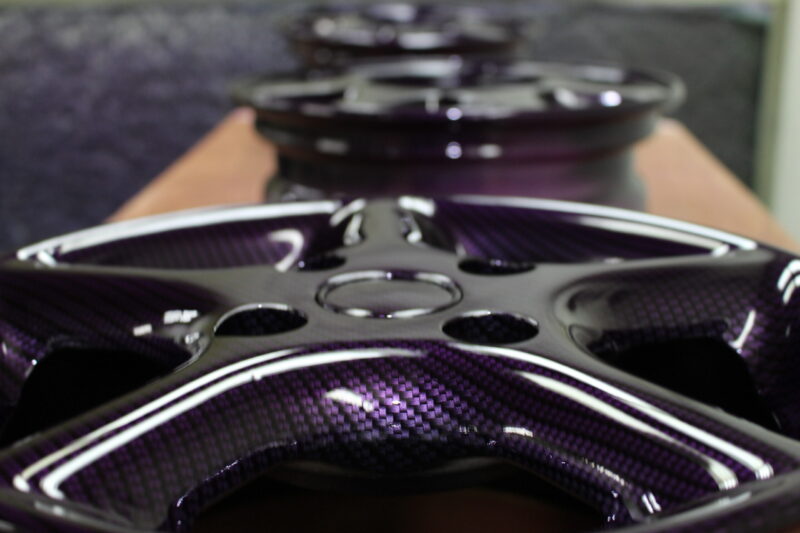 Car alloy wheels coated in carbon fibre painted magenta