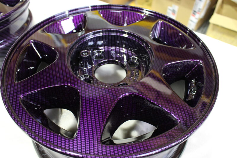 Car alloy wheels coated in carbon fibre painted magenta