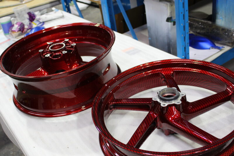 Motorbike alloy wheels coated in carbon fibre painted dark red