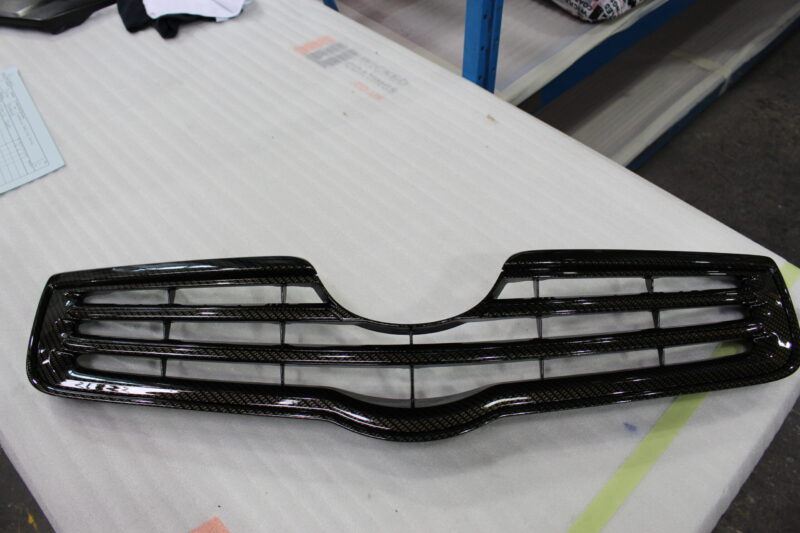 Radiator cover coated in carbon fibre