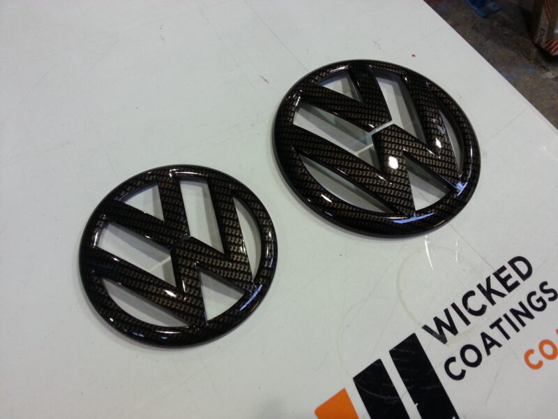 VW car badge coated in carbon fibre hydrographic film painted black