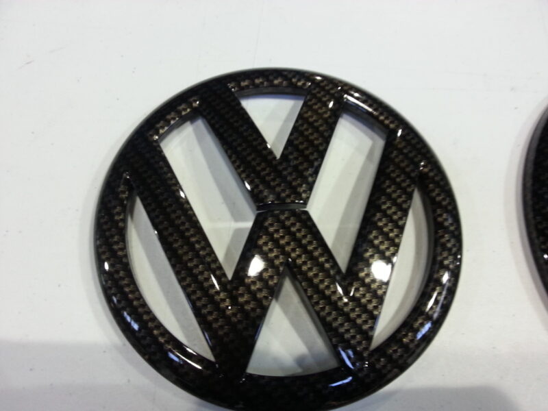 VW car badge coated in carbon fibre hydrographic film painted black