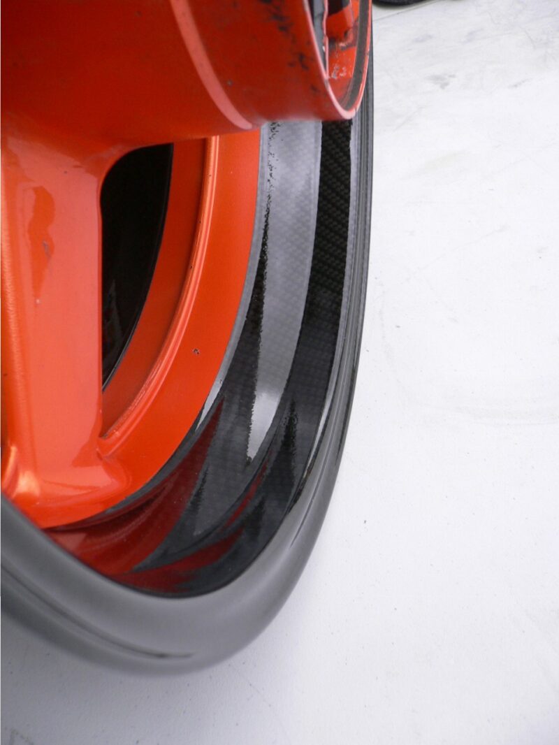 Motorbike alloy wheels coated in carbon fibre painted black and orange