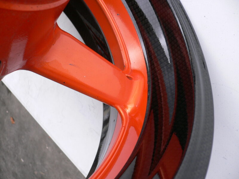 Motorbike alloy wheels coated in carbon fibre painted black and orange