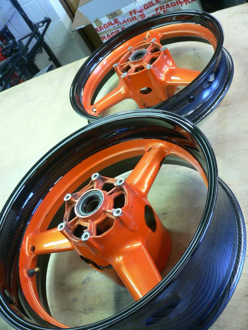 Motorbike alloy wheels coated in carbon fibre painted black and orange