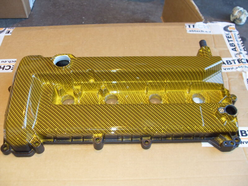 Car engine parts coated in carbon fibre painted yellow