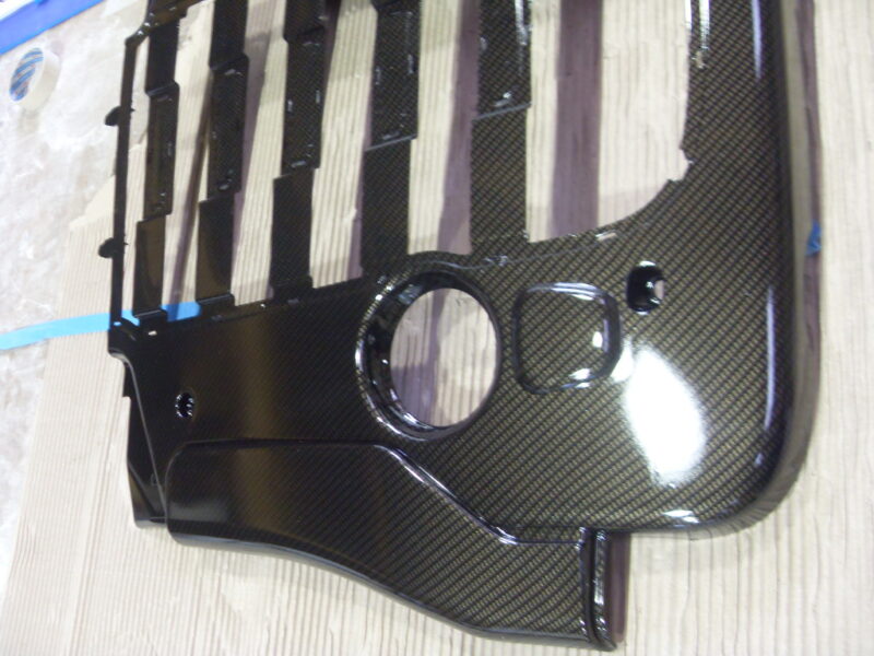 Car engine cover coated in carbon fibre hydrographic film painted black