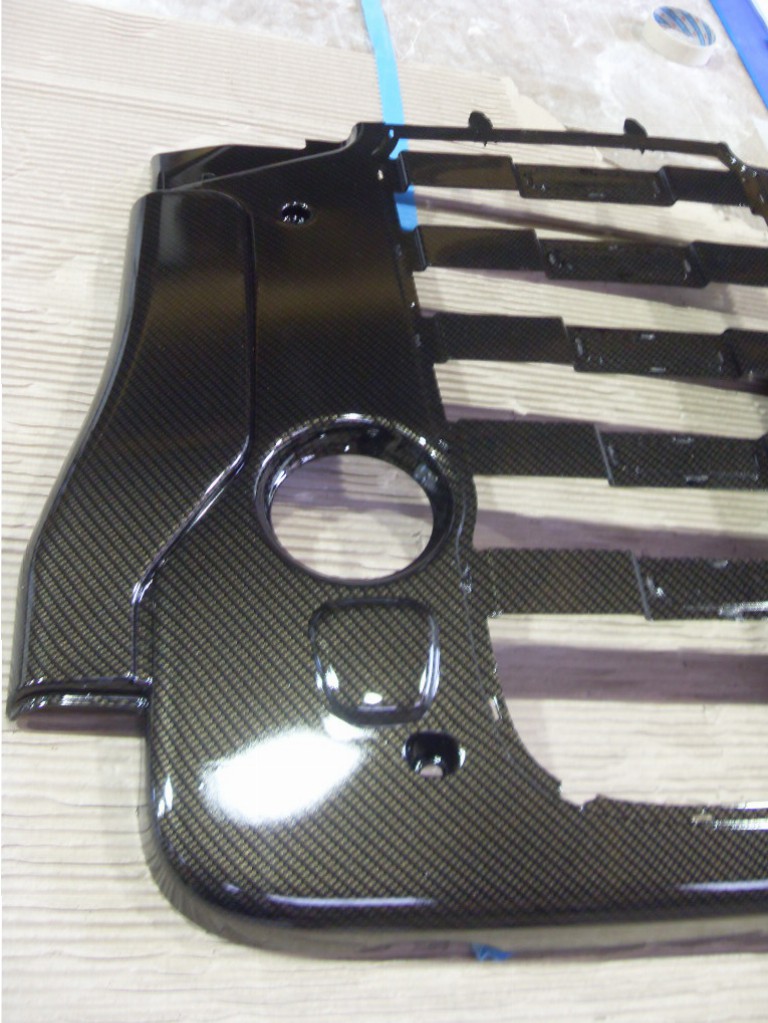 Car engine cover coated in carbon fibre hydrographic film painted black