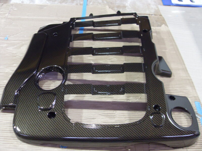 Car engine cover coated in carbon fibre hydrographic film painted black