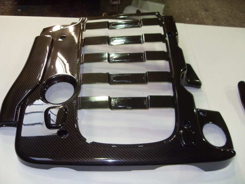 Car engine cover coated in carbon fibre hydrographic film painted black
