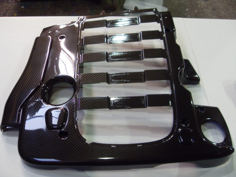 Car engine cover coated in carbon fibre hydrographic film painted black