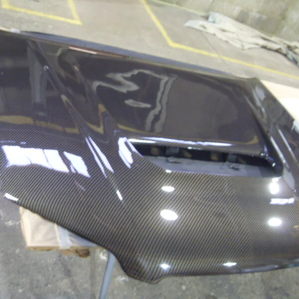 Car hood coated in carbon fibre hydrographic film painted black