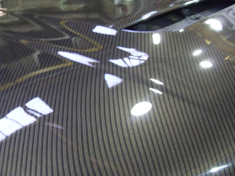Car hood coated in carbon fibre hydrographic film painted black
