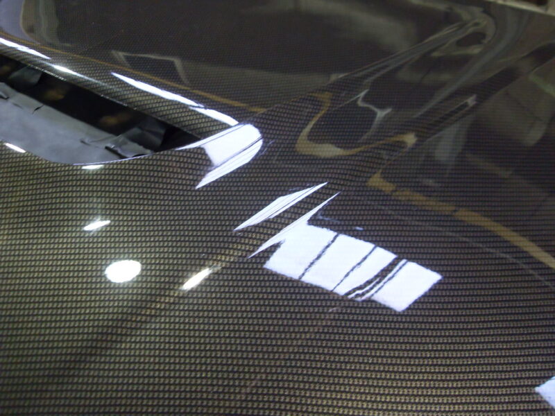 Car hood coated in carbon fibre hydrographic film painted black