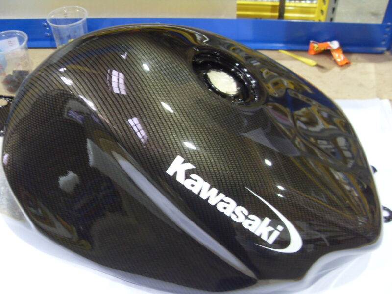 Motorbike tank coated in carbon fibre hydrographic film painted black