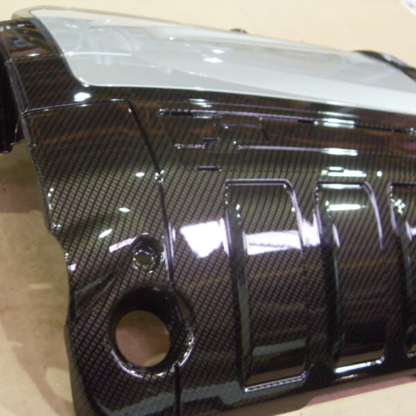 Engine cover coated in carbon fibre hydrographic film painted black