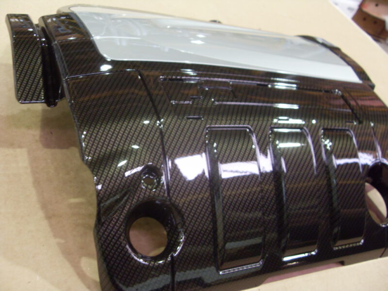 Engine cover coated in carbon fibre hydrographic film painted black