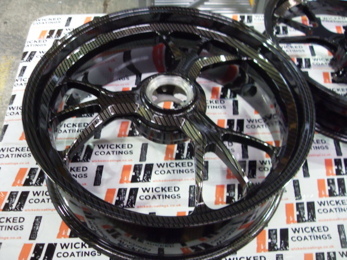 Motorbike alloy wheels coated in carbon fibre painted black