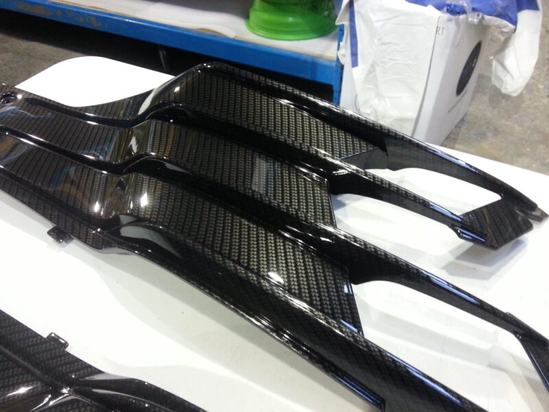 Motorbike parts coated in carbon fibre hydrographic film painted black