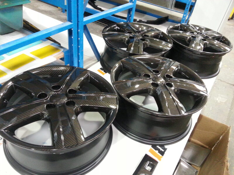 Car alloy wheels coated in carbon fibre hydrographic film painted black
