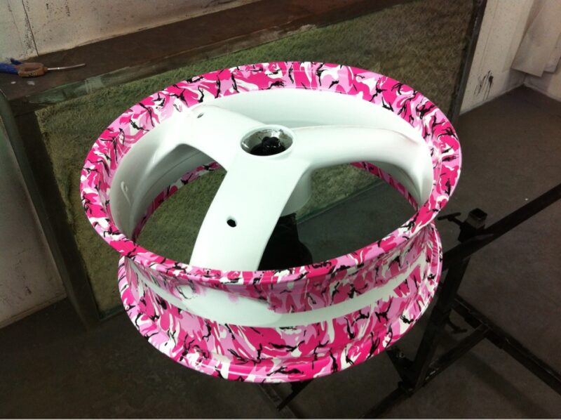 Pink abstract hydrographic film over white painted motorbike alloy wheels