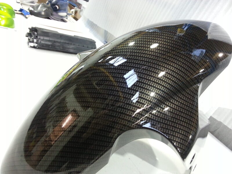 Motorbike parts coated in carbon fibre hydrographic film painted black