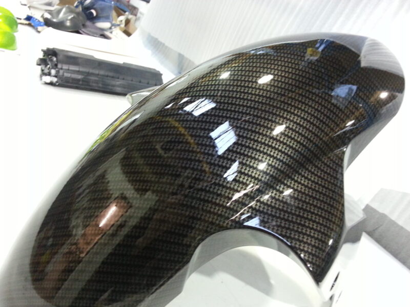 Motorbike parts coated in carbon fibre hydrographic film painted black