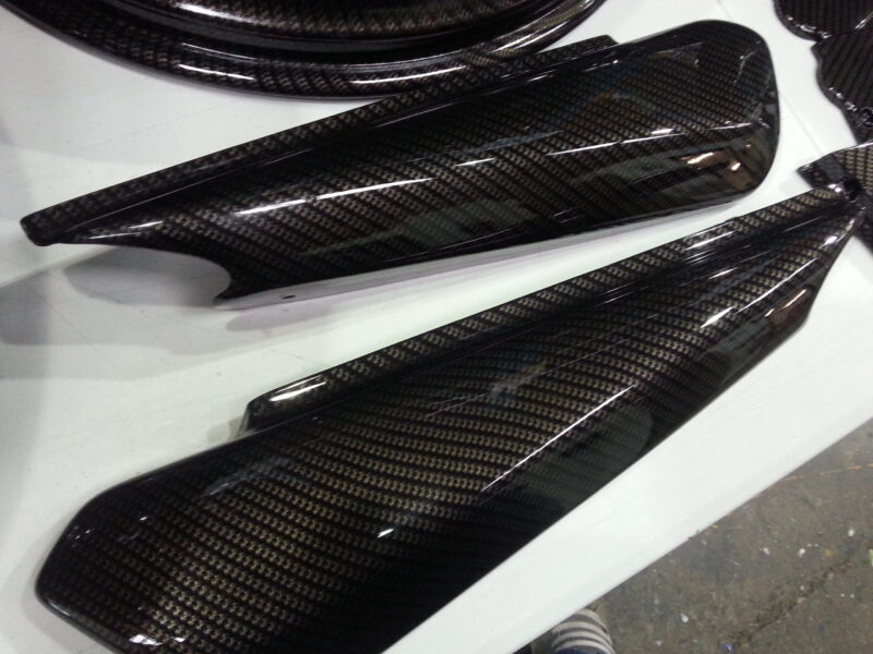 Motorbike parts coated in carbon fibre hydrographic film painted black