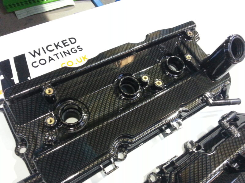 Car engine cover coated in carbon fibre hydrographic film painted black