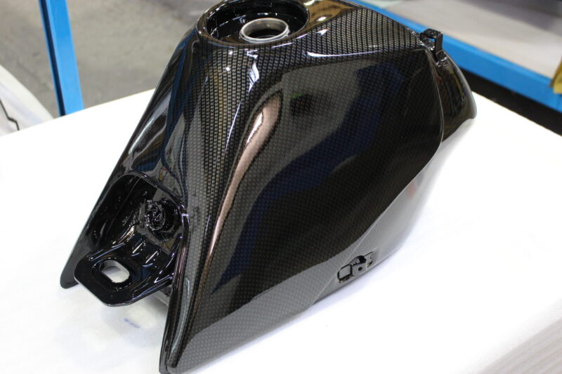 Motorbike tank coated in carbon fibre hydrographic film painted black