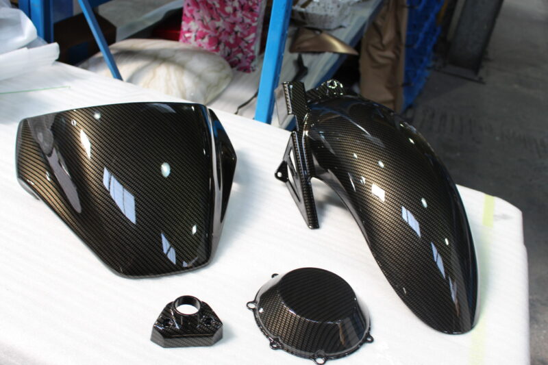 Motorbike parts coated in carbon fibre hydrographic film painted black