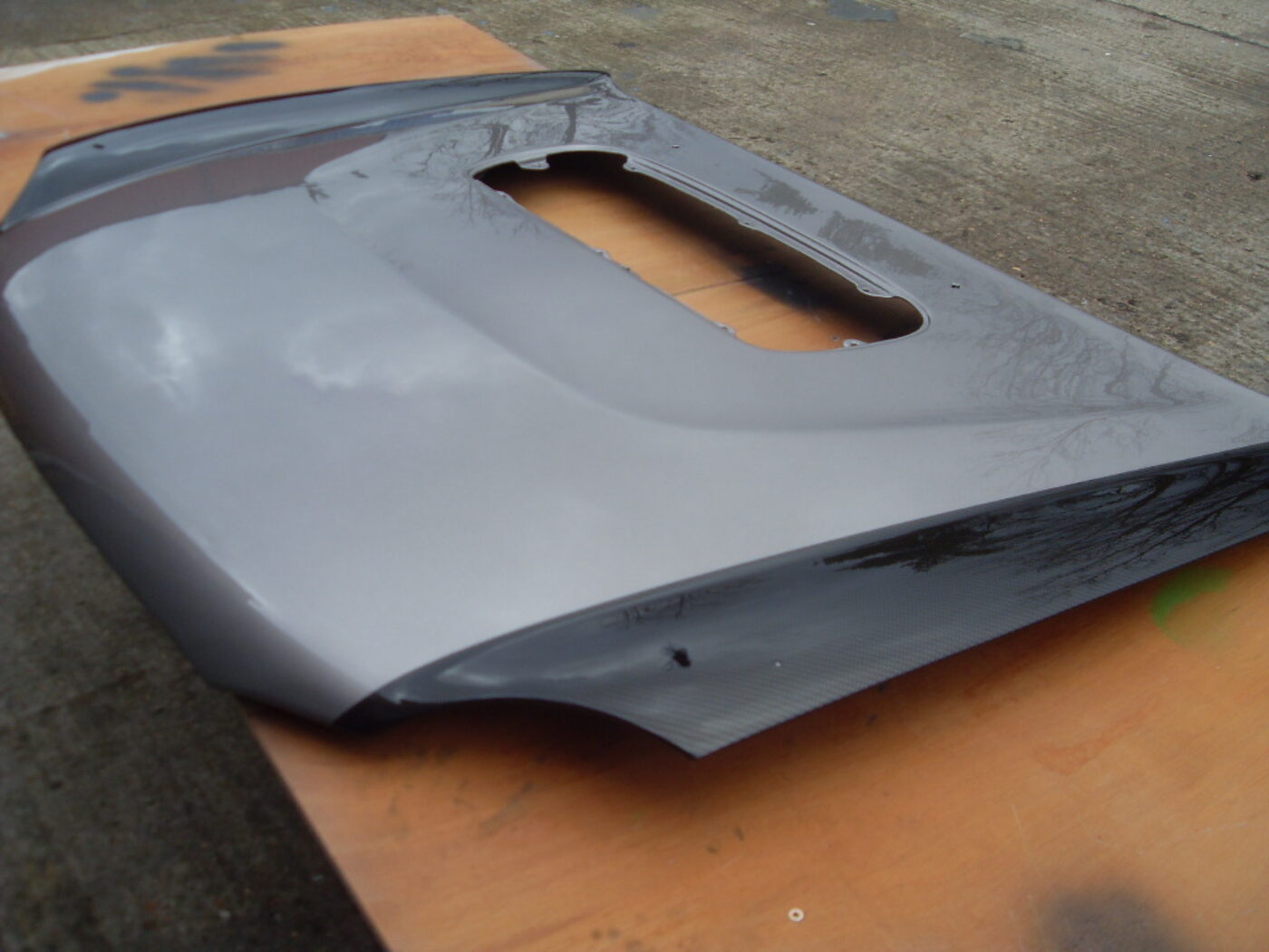 Car hood coated in carbon fibre hydrographic film painted black