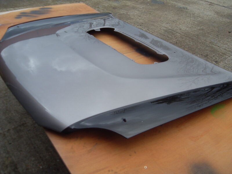 Car hood coated in carbon fibre hydrographic film painted black