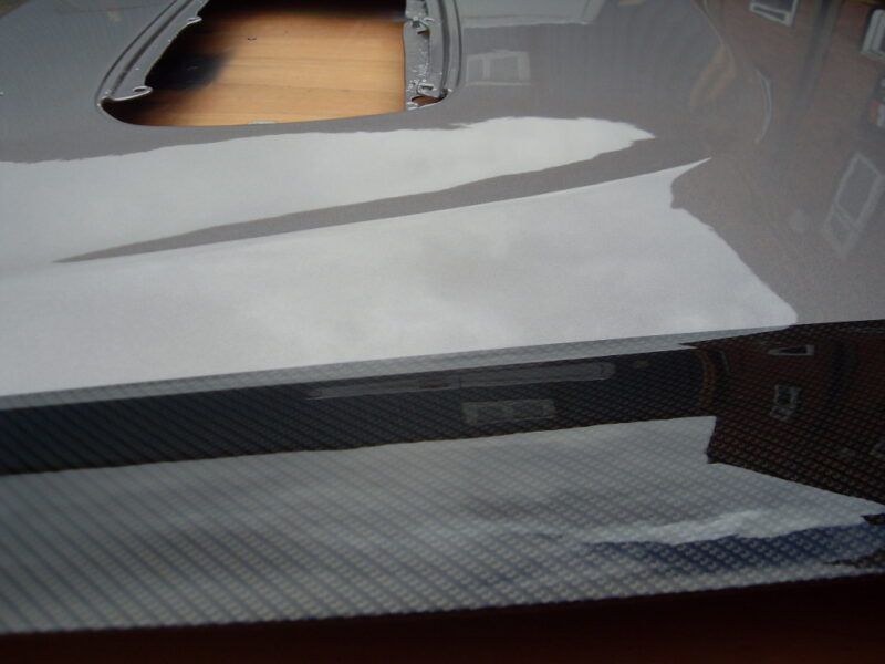Car hood coated in carbon fibre hydrographic film painted black